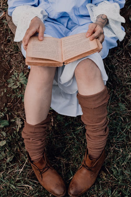 Photo of a Person with Brown Socks Reading a Book