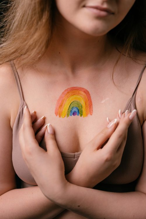 Free Close-up of a woman's chest with a rainbow tattoo symbolizing pride and individuality. Stock Photo