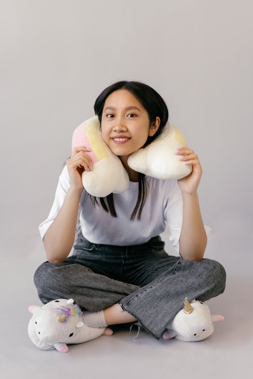 Woman in White Shirt Sitting on Floor with Pillow on her Neck