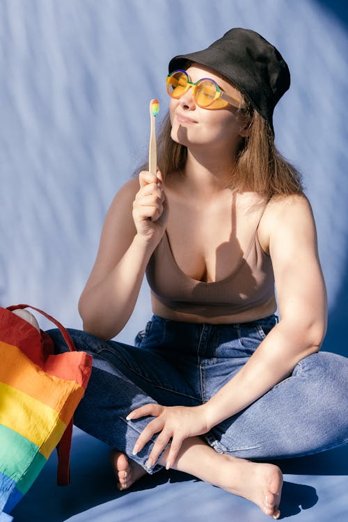 Woman in Brown Top and Colorful Sunglasses Wearing Denim Pants