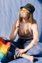 Woman in Pink Tank Top and Blue Denim Jeans Sitting on Bed