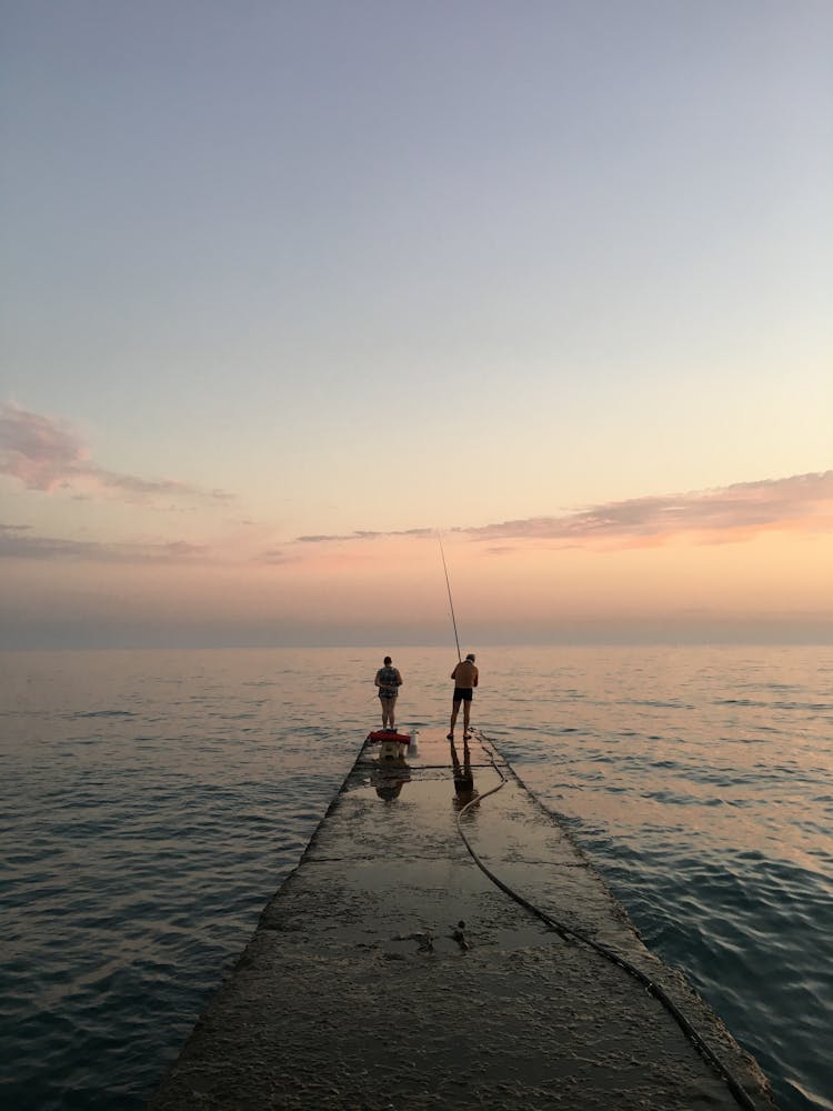 Two People Standing On Concrete Dock Fishing