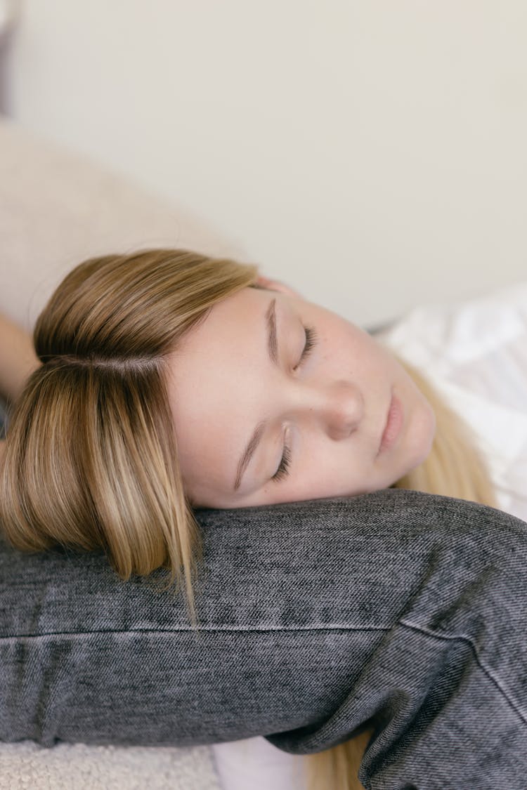 A Blonde Girl Sleeping On A Person's Leg