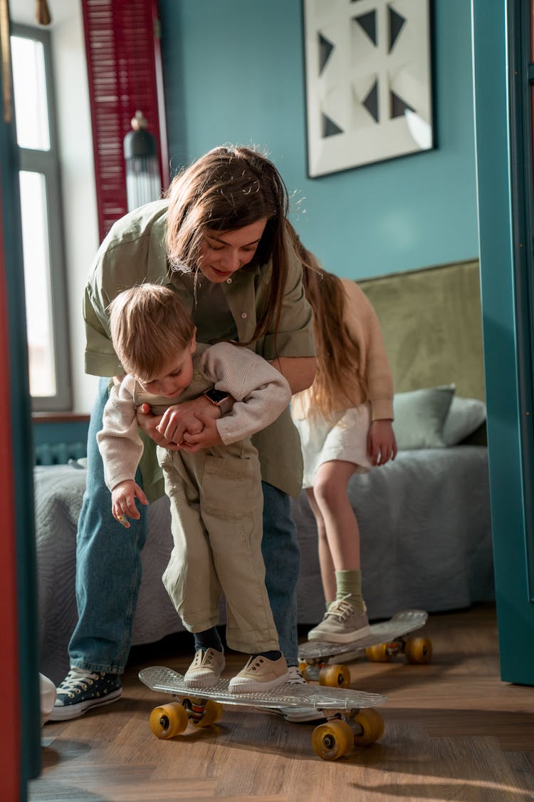 A Woman Teaching Her Son To Ride A Skateboard