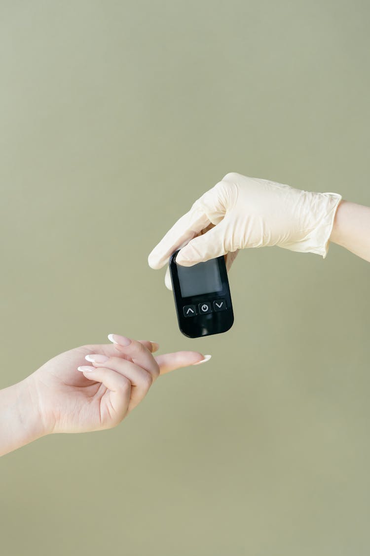 A Person's Hand Near A Glucometer