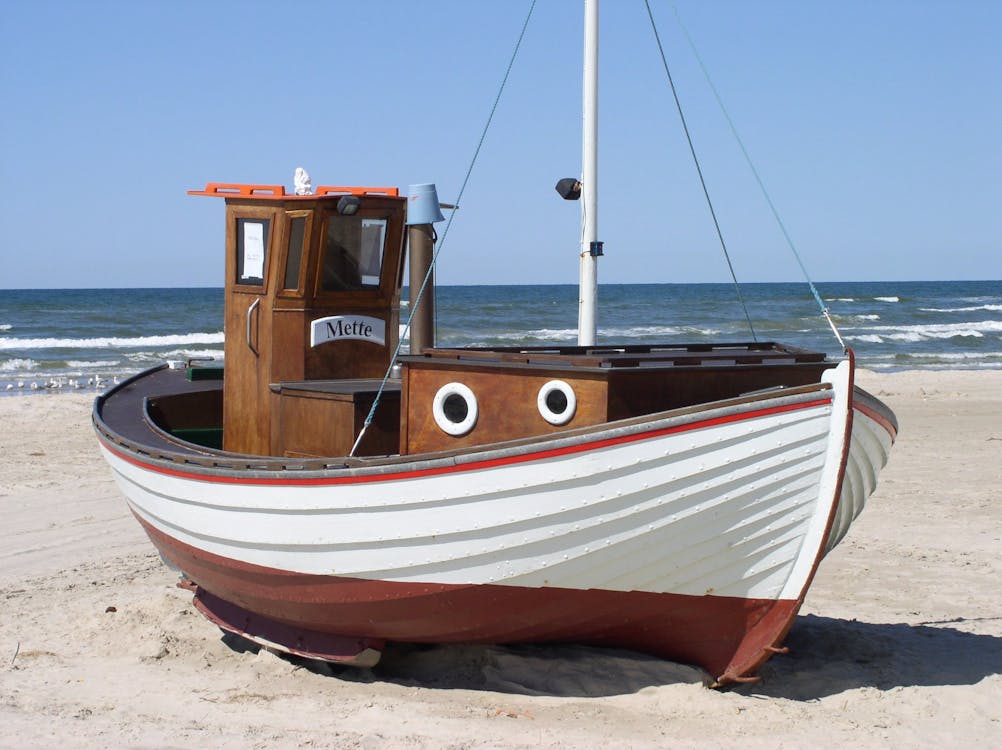 Free White and Brown Speedboat on White Sand Beside Ocean during Daytime Stock Photo