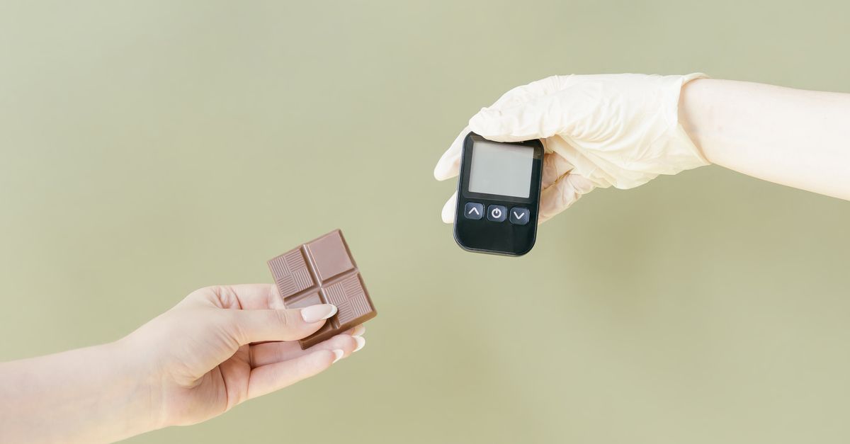 Close-up of hands holding a chocolate bar and glucose meter. - Evidence evidence guide for chlorogenic acid blood glucose meta-analysis