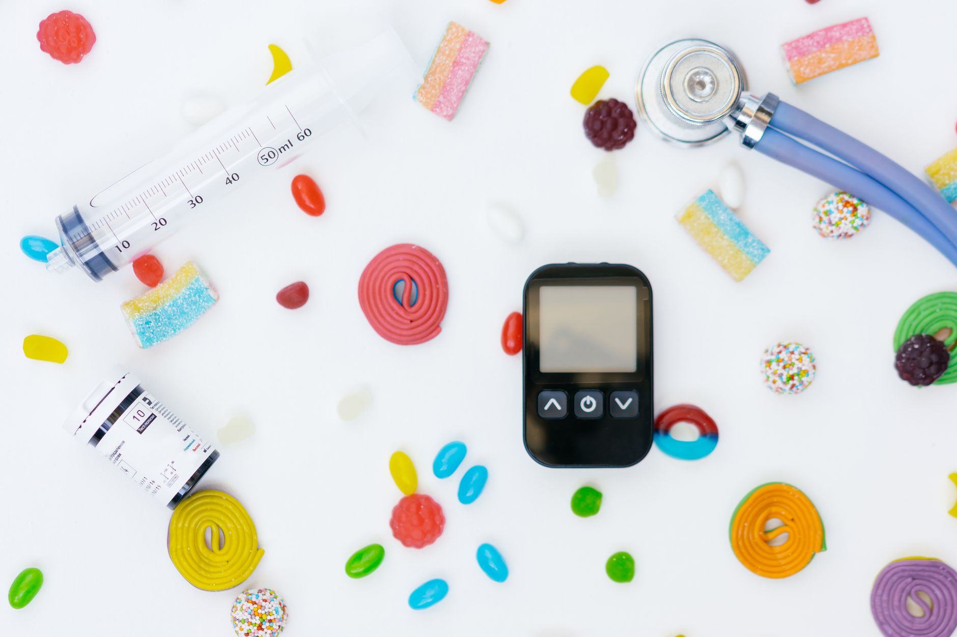GLP-1 meal planning, Ozempic diet - Flat lay of diabetes management tools and colorful candies on white background.