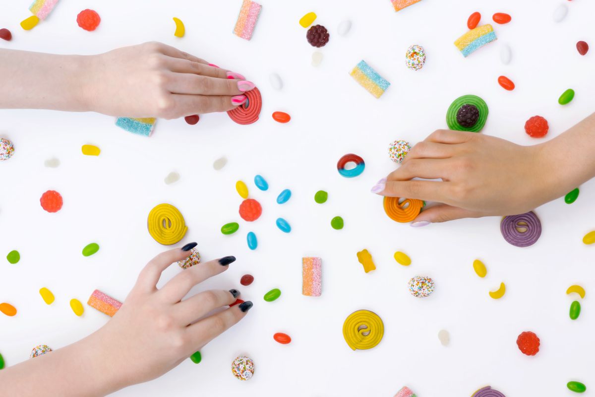 Playful scene of diverse candies and hands on a white background, radiating joy and sweetness.