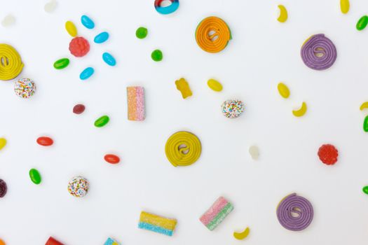 Vibrant flat lay of assorted colorful candies and sweets on a white background.