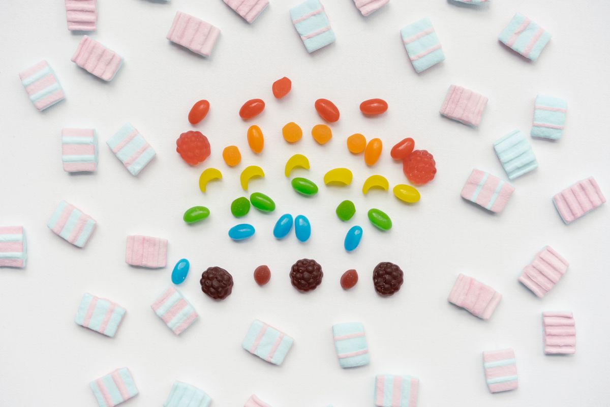 Vibrant arrangement of assorted candies on a white surface, showcasing playful colors.