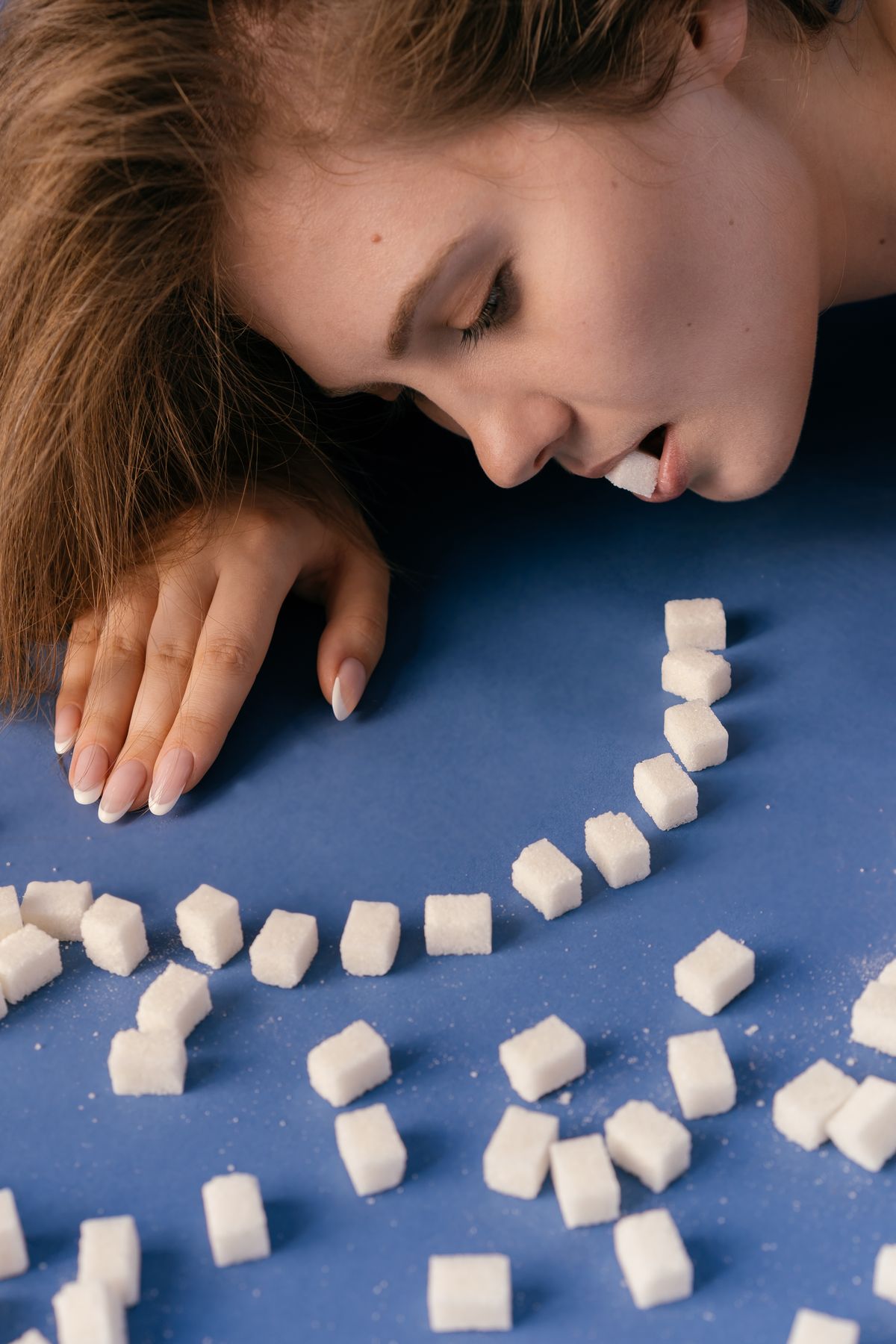 Mulher mordendo um cubo de acucar simbolizando vontade de comer doce