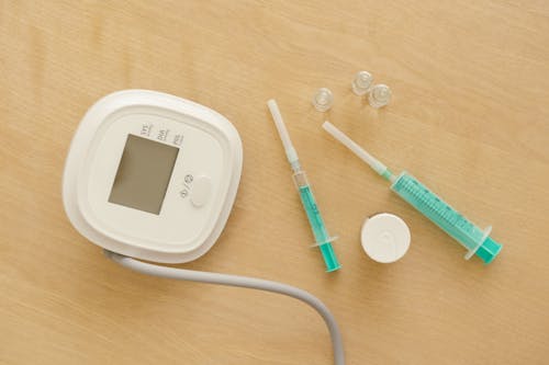 

A Close-Up Shot of Syringes and a Digital Sphygmomanometer