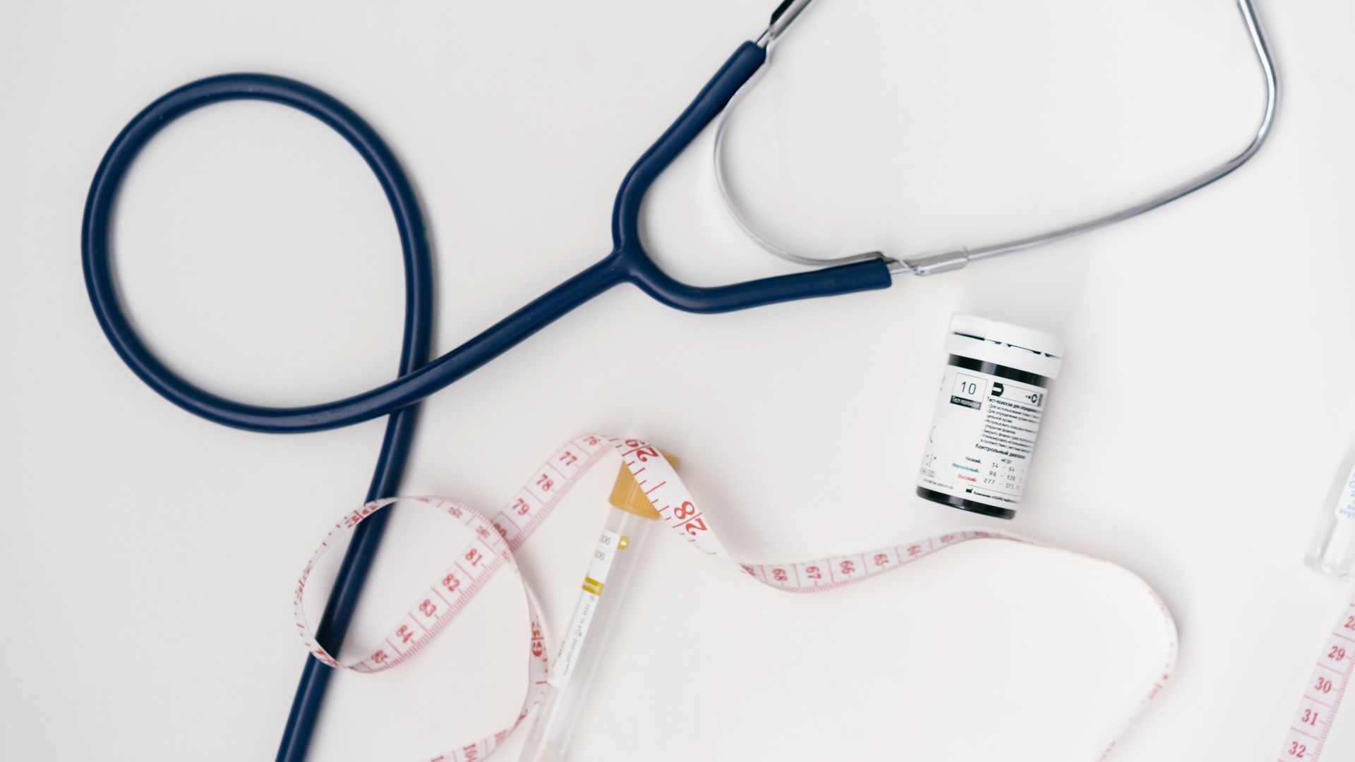 Flat lay of medical tools including stethoscope and measuring tape on a white background — how to health