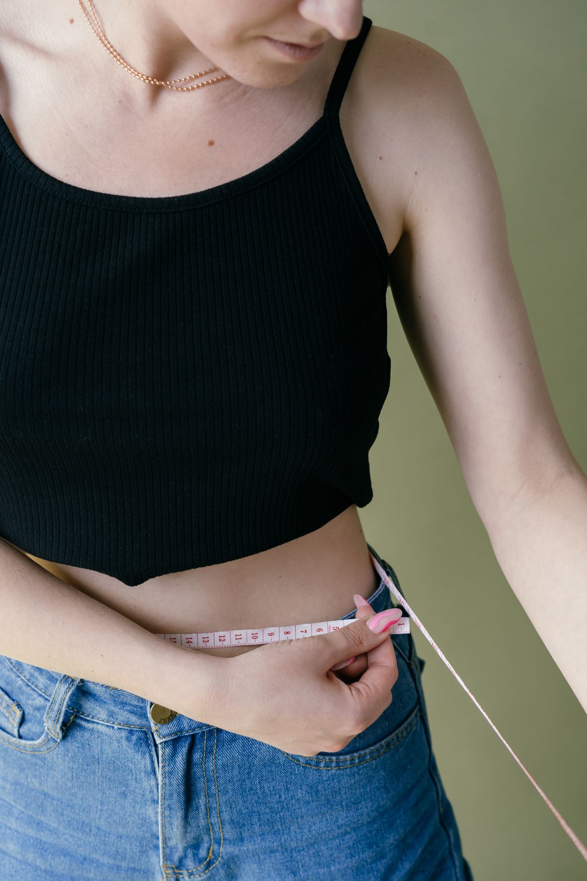 Person measuring their waist with a tape measure for fitness tracking