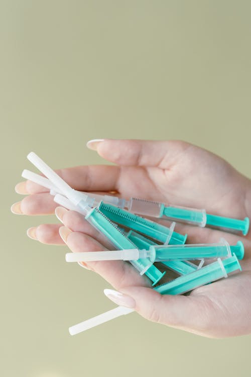Close-Up Shot of a Person Holding Syringes