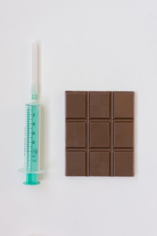 Bar of Chocolate and Syringe on White Table