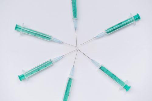 Free Abstract arrangement of medical syringes forming a star pattern on a white surface. Stock Photo