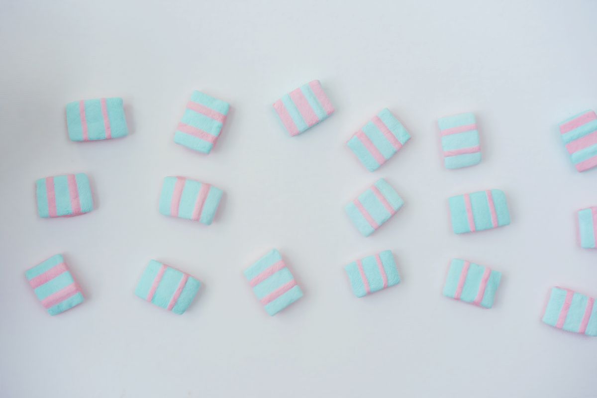 Close-up of pastel pink and blue striped candies on a white background, offering ample copy space.