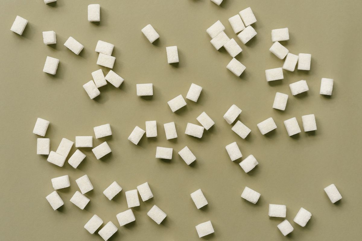 A top-down view of sugar cubes scattered over an olive green background.