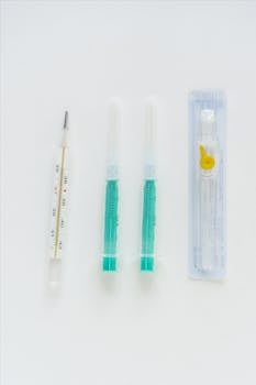 Minimalist photo of syringes and thermometer against a white background.