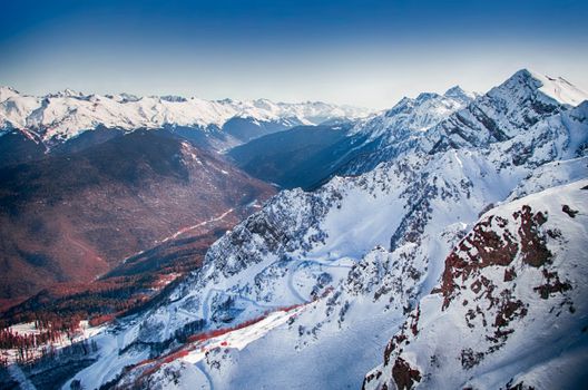 Stunning aerial view of the snow-covered mountain ranges in Sochi, Russia, showcasing winter beauty.