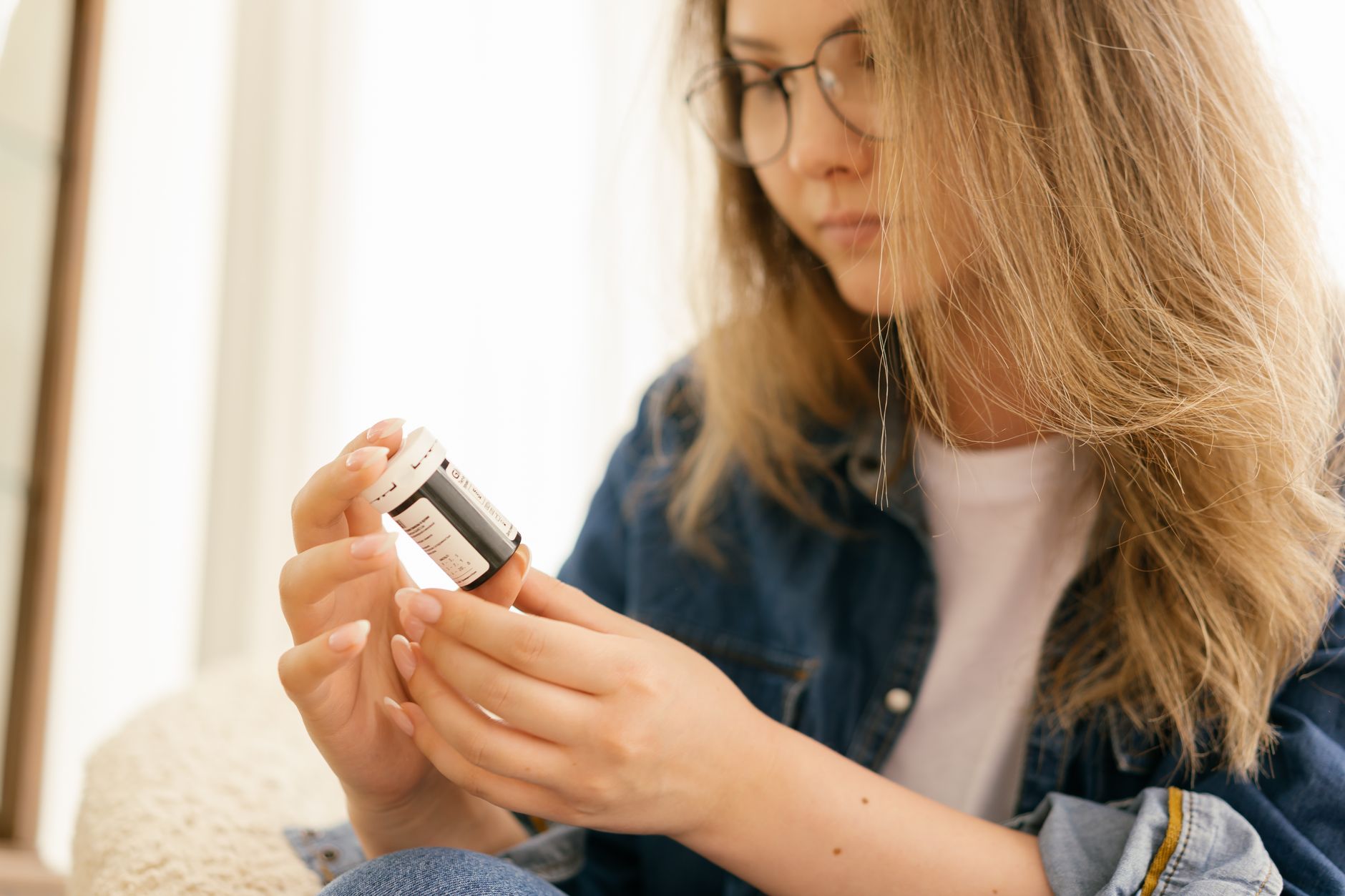 A woman examining a medication bottle and label carefully