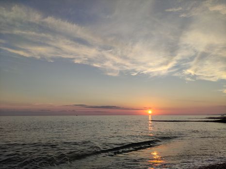 Peaceful ocean sunset with soft waves and colorful sky.