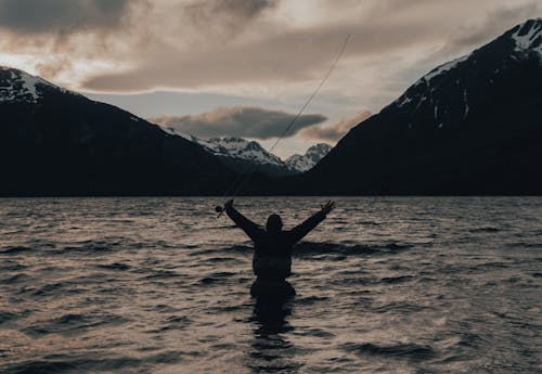 Person Standing on Shallow Water While Fishing