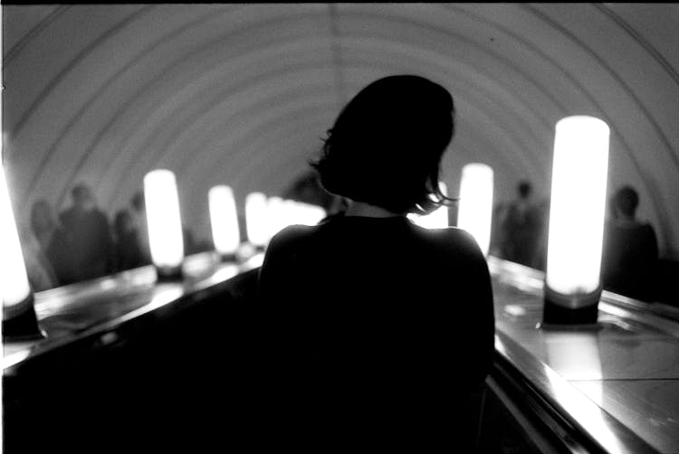 Back View Of A Woman Going Down The Escalator