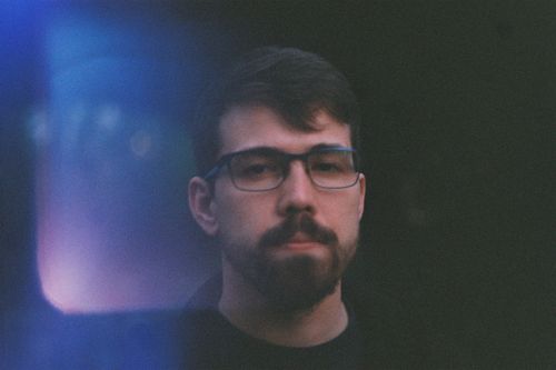 Free A contemplative portrait of a bearded man wearing glasses, with moody lighting. Stock Photo