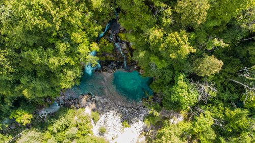 Free A breathtaking aerial view of a tranquil waterfall and pool surrounded by lush forest greenery. Stock Photo