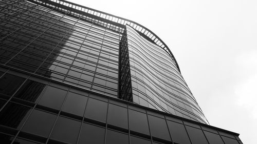 Free Low-angle view of a modern high-rise building with glass facade in black and white. Stock Photo