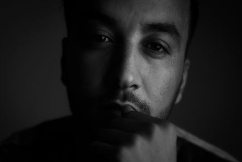 Free A dramatic black and white portrait capturing a man's serious expression in low light. Stock Photo