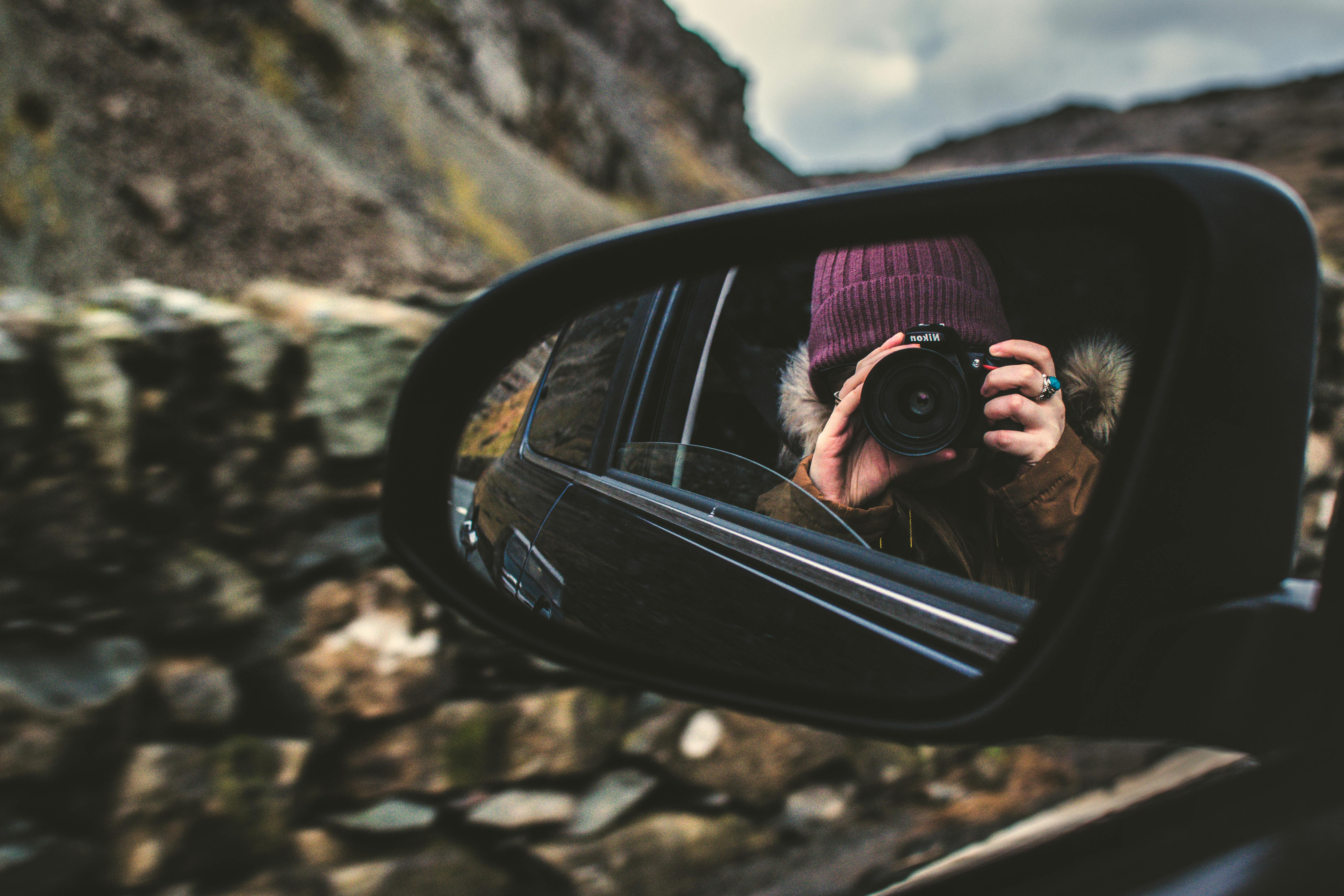 Person Holding Dslr Camera Reflected on Black Framed Wing Mirror