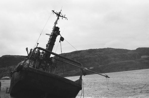 Free A dramatic black and white image of a tilted shipwreck on a rocky coastline. Stock Photo