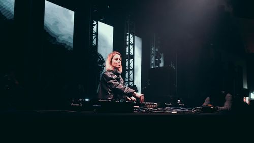 Free A female DJ playing an energetic live set onstage with dynamic lighting and visuals. Stock Photo