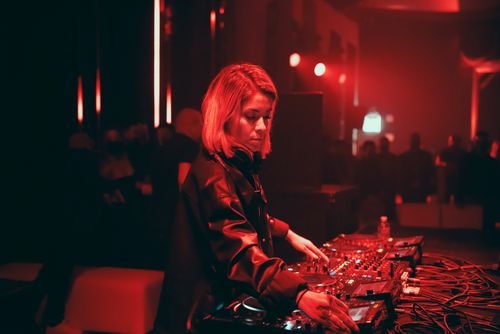Free Female DJ mixing tracks in a vibrant nightclub with red lighting ambiance. Stock Photo