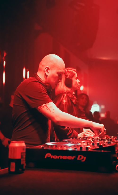 Free DJ skillfully mixes tracks in a vibrant nightclub setting, creating an electrifying atmosphere. Stock Photo