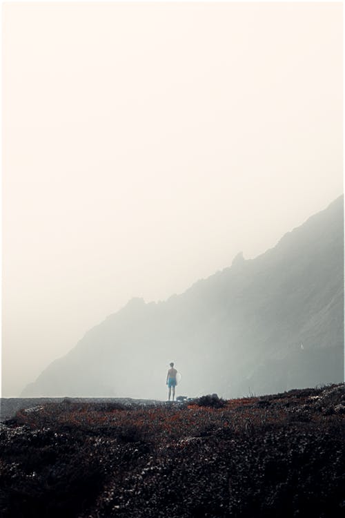 Person Standing Near Mountain on a Foggy Day