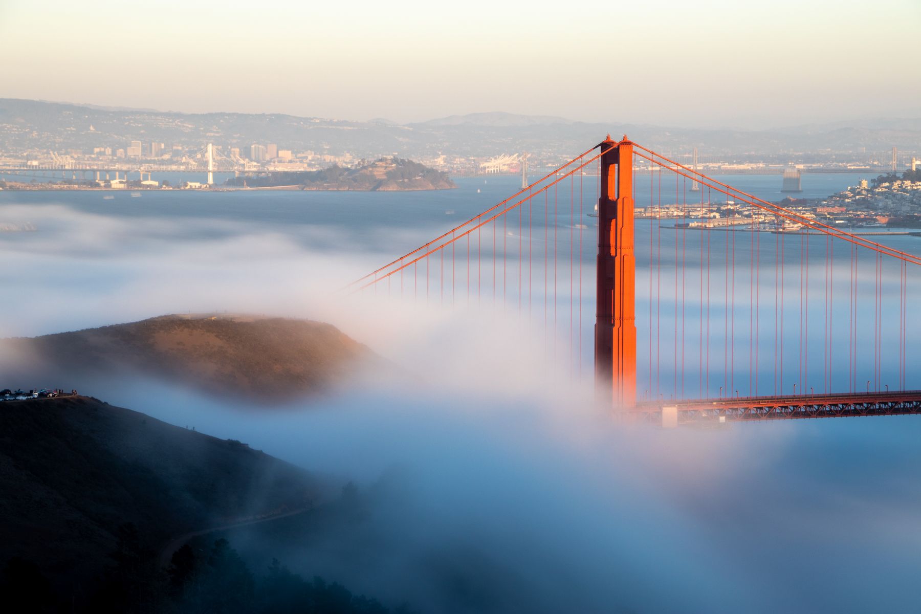 The Golden Gate Bridge emerging from fog at sunrise in San Francisco