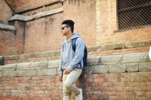 Man posing against the historic bricks of Bhaktapur, showcasing casual style.