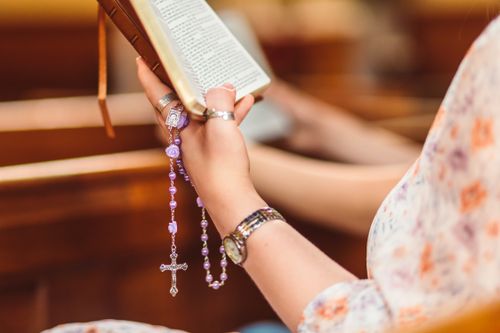 Free A woman reads a Bible in church while holding a rosary, showcasing faith and reflection. Stock Photo