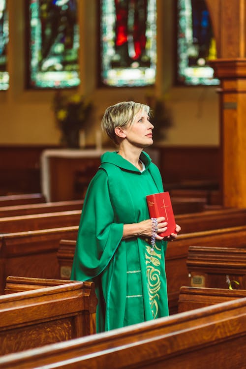 Free Woman in Green Cassock Holding a Bible Stock Photo