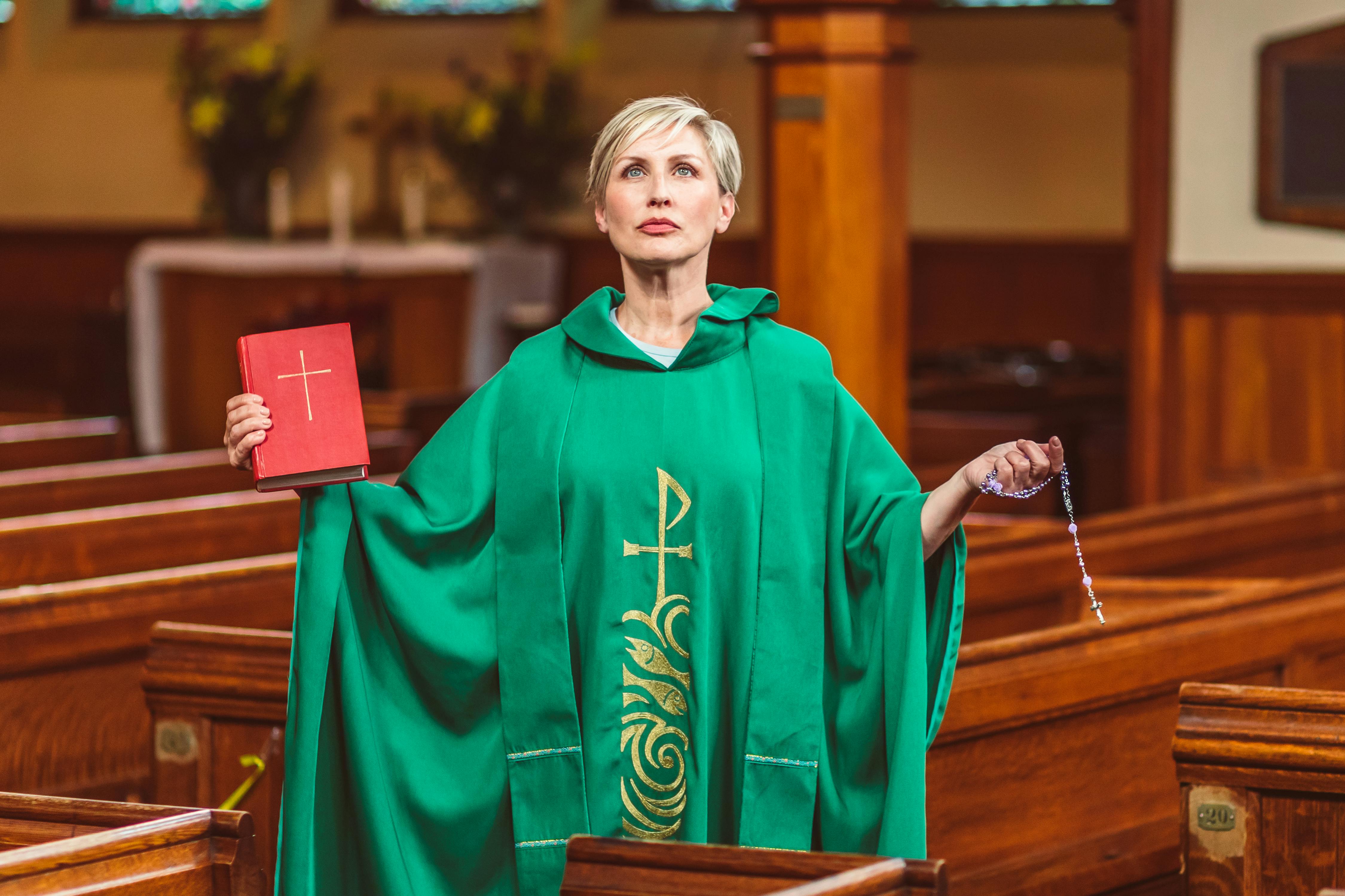 a woman wearing a green cassock holding a bible and a rosary