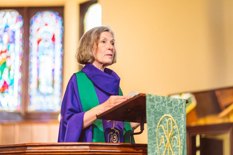 Woman Wearing A Purple Chasuble Standing Behind A Lectern 