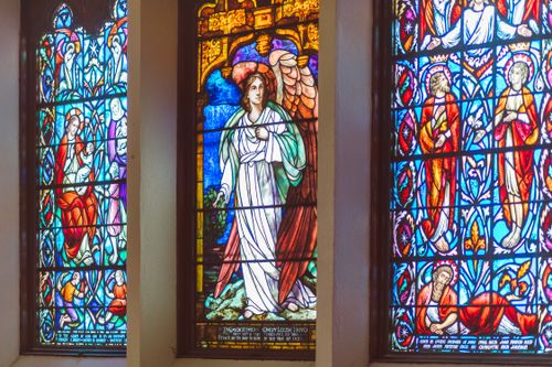 Free Vibrant stained glass windows depicting religious figures in a church setting. Stock Photo