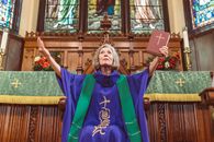 Elderly Woman in Purple Cassock Holding a Bible