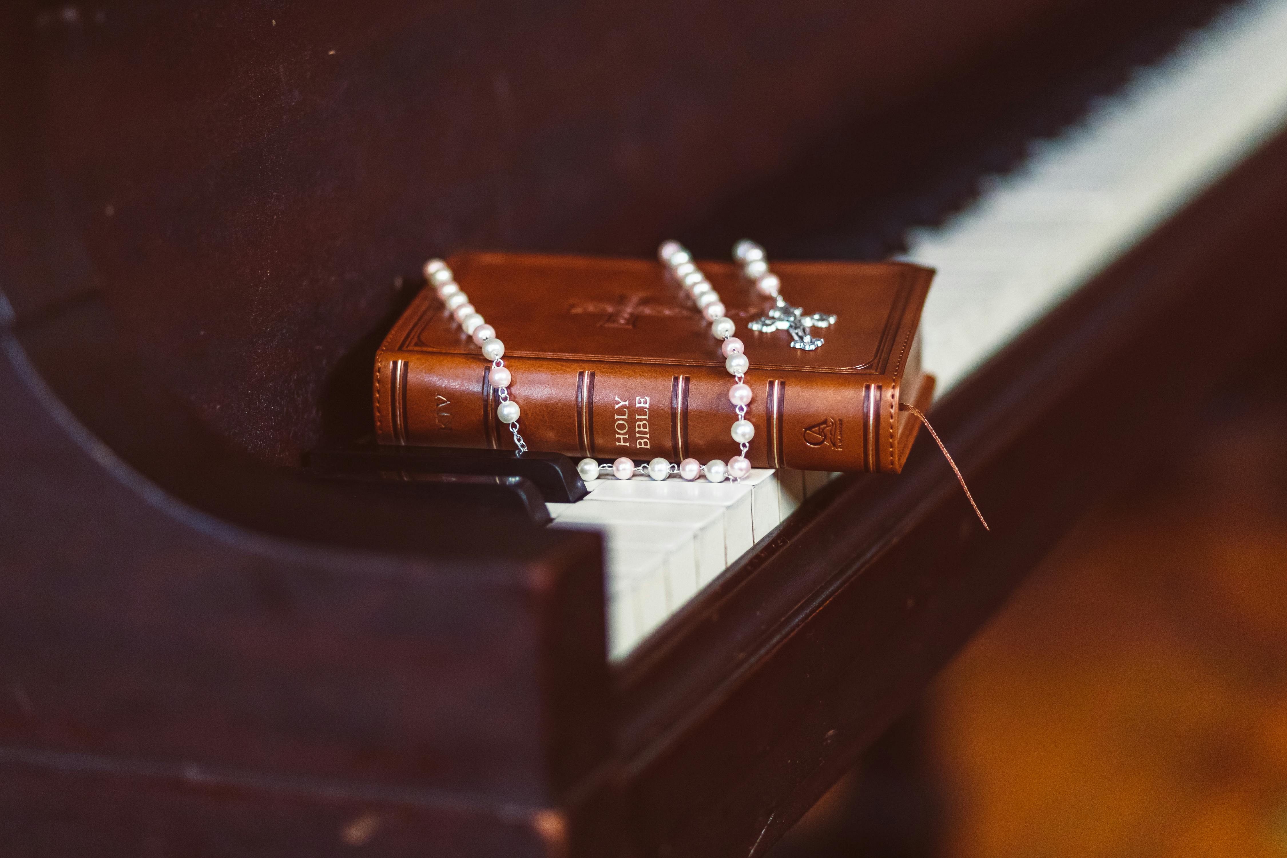 brown bible book on top of piano keys