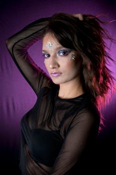 Elegant portrait of a woman with stylish makeup and rhinestones on a purple background.